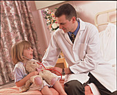 Doctor talks with young girl in a paediatric ward
