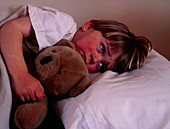Three year-old child in bed with teddy bear