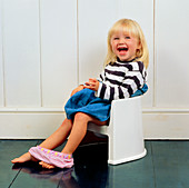 A laughing young girl using a potty