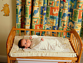 Baby lying on its back awake in a cot