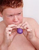 Boy blowing up a balloon