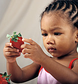 Young girl holding a strawberry