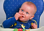 Nine-month-old baby eating a biscuit