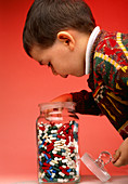 Boy taking pills and drug capsules from a jar