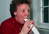 Woman breathes into a peak flow meter tube