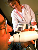 Technician watches man breathe into spirometer