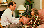 GP talking to elderly woman during home visit