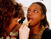 Nurse using spatula to examine woman's throat