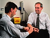 GP doctor measures pulse of elderly man