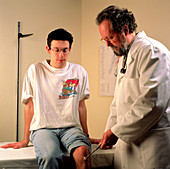 Doctor tests the knee jerk reflex of a young man