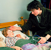 GP doctor on home visit examines feverish child