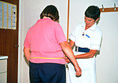 Nurse measuring an obese woman's waist