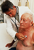 Doctor using stethoscope on elderly man's chest