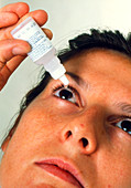 Woman applying eye drops to her eye