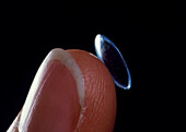 Close-up of hard contact lens on finger