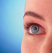 Close-up of a woman's blue eye with a tear-drop