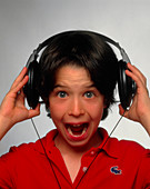 Young boy hearing a loud sound through headphones