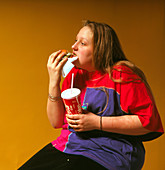 Adolescent girl eating hamburger & drinking Coke