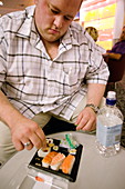 Obese man eating sushi