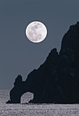Full moon rising over a coastal cliff