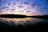 Sunset over lake with broken stratus clouds