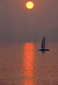 Sun setting over the sea with sailing boat