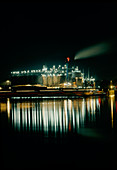 Oil refinery at night with reflections from water