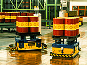 Robots transporting oil drums in a production hall