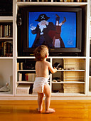 Child watches television using remote control
