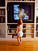Young child stands and watches television
