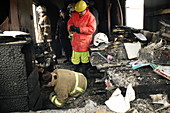 Firefighters in a burnt-out house