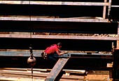 Construction site: workman secures steel girders