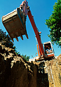 Mechanical digger excavates ditch on building site