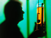 Silhouette of a chemist holding a glass cylinder