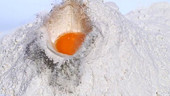 Egg falling in flour