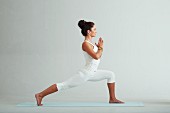 Krieger 2, Schritt 1: Fuß nach vorne, hinteres Bein gestreckt und Hände in Gebetshaltung (Power-Yoga)