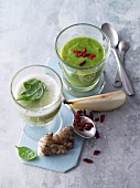 Two green smoothies garnished with spinach and goji berries