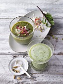 Two green smoothies garnished with bean sprouts and cardamom