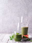 Two green smoothies garnished with lamb's lettuce and watermelon