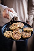 A man holding a pan of quinoa and cauliflower fritters with wild garlic