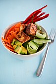 A bowl of sushi with tofu and vegetables