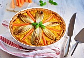 Chicory and carrot tart in a baking dish on a tea towel