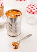 Dulce de leche in a tin and on a spoon