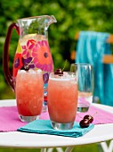 Two glasses of cherry apple gin fizz on a garden table