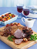 Roast leg of lamb with a side of vegetables, gravy and wine