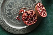 A halved pomegranate on a decorative metal plate