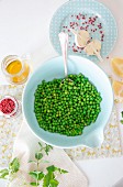An arrangement of ingredients with green peas, pink pepper, garlic, oil and mint