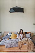 Woman sitting on bed using tablet computer