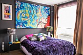 Buntes Bild mit Graffito über Bett mit violetter Felldecke
