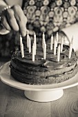 A chocolate cake being decorated with birthday candles